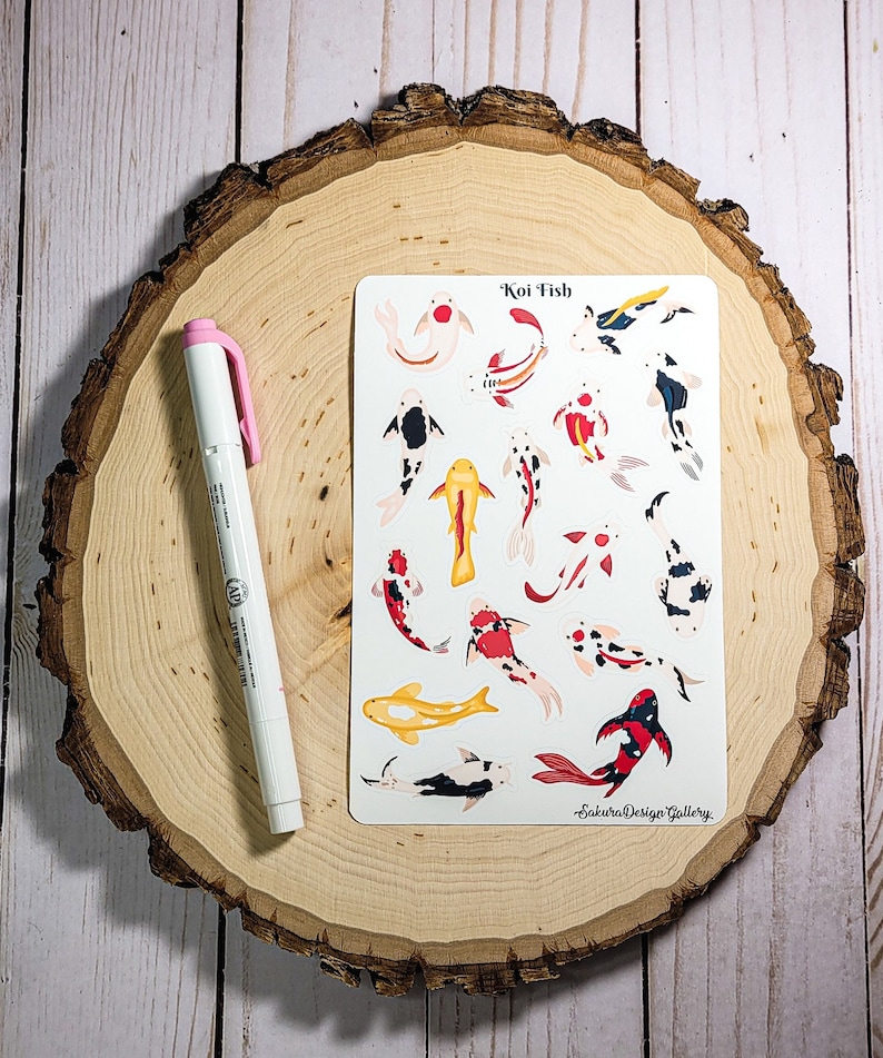 May include: A sheet of stickers featuring colorful koi fish illustrations. The stickers are on a white background and have the text "Koi Fish" at the top. The text "Sakura Design Gallery" is at the bottom of the sheet.