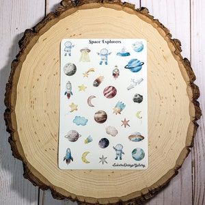 May include: A sheet of stickers with a space theme, featuring astronauts, planets, rockets, stars, and UFOs. The text "Space Explorers" is at the top. The stickers are on a white background, with the "Sakura Design Gallery" logo at the bottom.