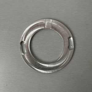May include: A silver metal ring with two small holes on either side. The ring has a smooth, polished finish.