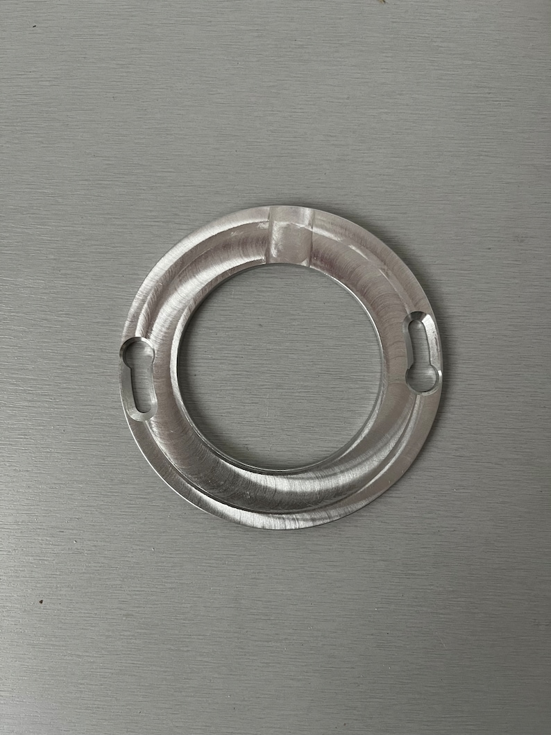 May include: A silver metal ring with two small holes on either side. The ring has a smooth, polished finish.