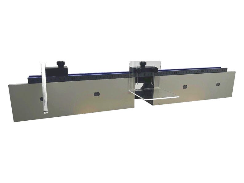 May include: A silver-colored woodworking tool with a black and blue ruler and clear plastic components. The tool has adjustable parts and is designed for precise measurements and cuts. It is set against a white background.