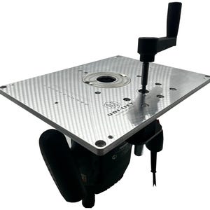 Op de afbeelding: Een zilveren freestafel met een zwarte handgreep en een zwarte motor. De tafel heeft een rechthoekige vorm met een getextureerd oppervlak en verschillende gaten. De tekst "UNI-LIFT" is zichtbaar op de tafel.
