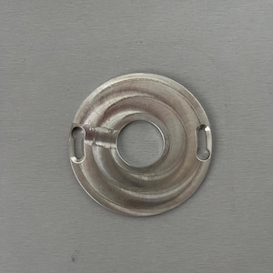 May include: A silver metal ring with a circular design and two small tabs on the sides. The ring has a smooth, polished finish.