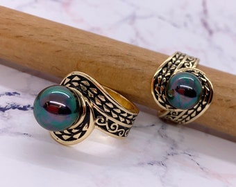 May include: Two gold rings with black and gold designs. Each ring features a large, iridescent black pearl.