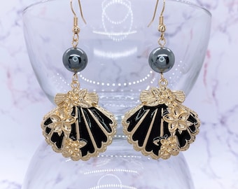 May include: Gold tone earrings with black enamel seashell charms and black beads.
