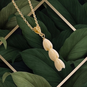 May include: A gold chain necklace with a pendant made of carved white bone. The pendant is shaped like a cluster of five flower buds.