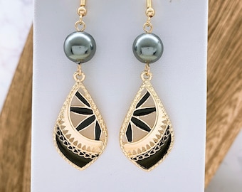 May include: Gold dangle earrings with black and white enamel designs and a single black pearl on each earring.