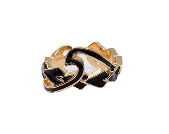 May include: Gold ring with black enamel detailing in the shape of interlocking hearts.