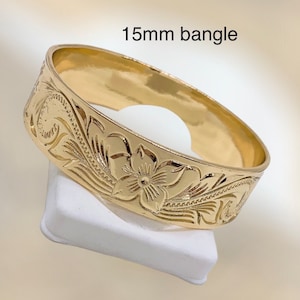 Puede incluir: Un brazalete de oro de 15 mm con un dise&ntilde;o floral. El brazalete est&aacute; hecho de oro pulido y tiene un acabado liso.