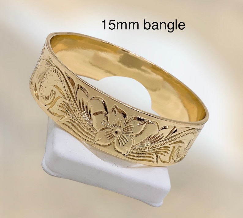 Puede incluir: Un brazalete de oro de 15 mm con un dise&ntilde;o floral. El brazalete est&aacute; hecho de oro pulido y tiene un acabado liso.