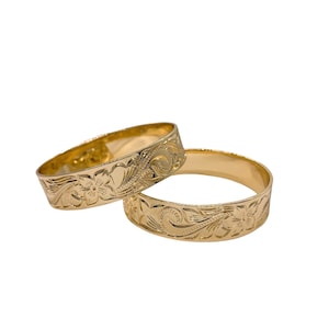 Puede incluir: Dos anillos de oro con un dise&ntilde;o floral. Los anillos est&aacute;n apilados uno encima del otro.