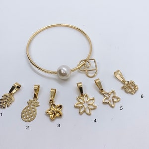 May include: A set of ten gold charms, including a pineapple, a flower, a leaf, and a butterfly. The charms are on a white background.