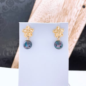 May include: A pair of gold flower-shaped earrings with black pearl drops.