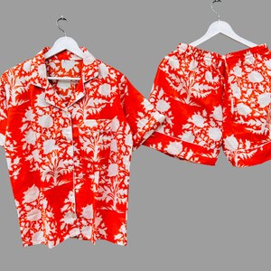 May include: A red and white floral print pajama set with a short-sleeved button-up shirt and matching shorts.