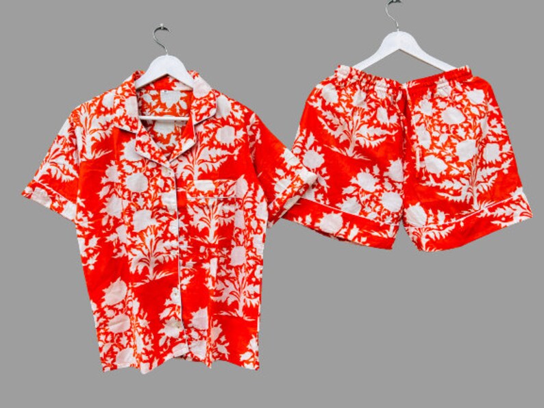 May include: A red and white floral print pajama set with a short-sleeved button-up shirt and matching shorts.