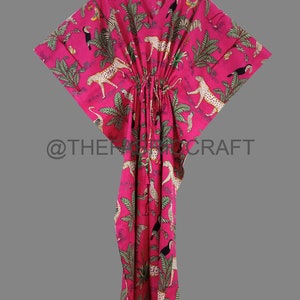 Op de afbeelding: Een roze kaftan met een jungleprint met luipaarden, toekans, zebra's en palmbomen. De kaftan heeft een V-hals en een trekkoord in de taille.