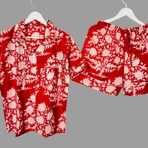 May include: Red and white floral print pajama set with a short-sleeved button-up top and matching shorts.