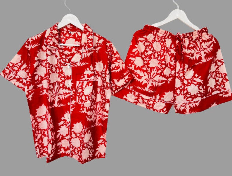 May include: Red and white floral print pajama set with a short-sleeved button-up top and matching shorts.