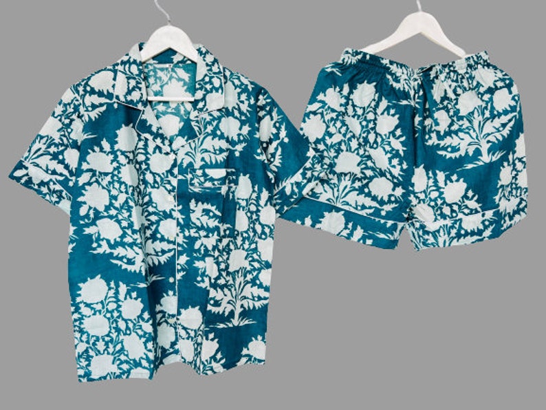 May include: A teal blue pajama set with a white floral print. The top has a collared neckline and short sleeves. The shorts have an elastic waistband.