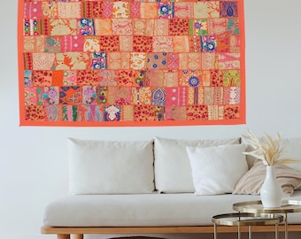 May include: A colorful patchwork wall tapestry with a variety of floral and geometric patterns in shades of orange, pink, and blue. The tapestry is framed with a bright orange border.