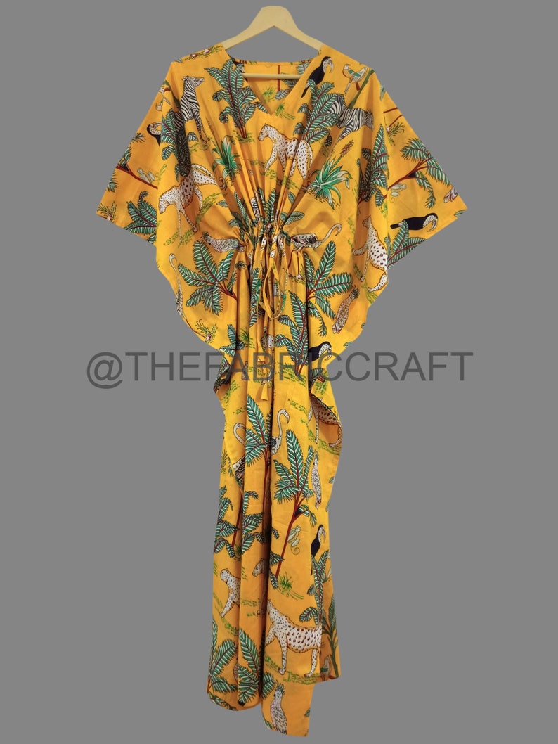 Op de afbeelding: Gele kaftan met een jungleprint met toekans, zebra's en luipaarden. De kaftan heeft een trekkoord in de taille en korte mouwen.