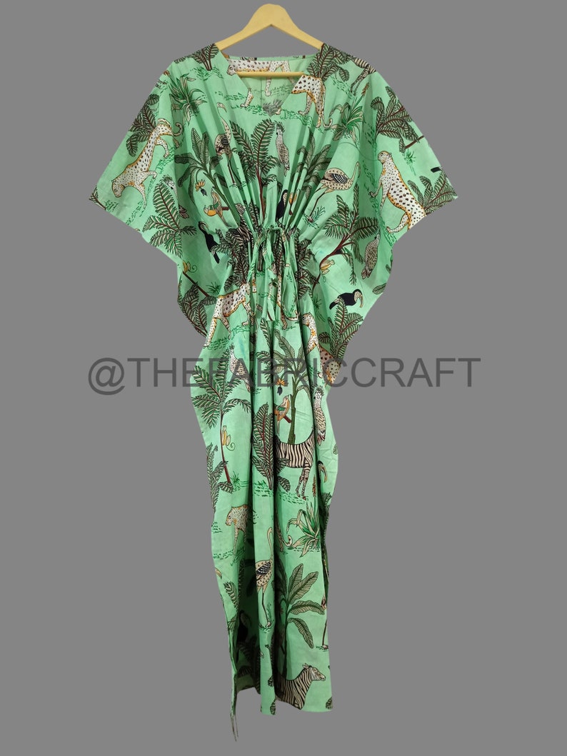 Op de afbeelding: Een groene kaftan met een jungleprint met zebra's, luipaarden en toekans. De kaftan heeft een trekkoord in de taille en korte mouwen.