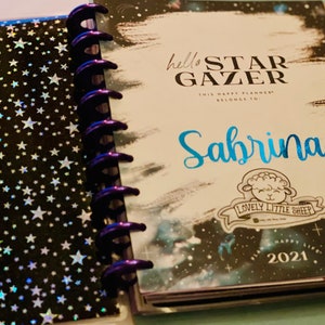 Może przedstawiać: Czarno-biały planer z wzorem galaktyki i tekstem "hello star gazer this happy planner belongs to: Sabrina" ze  naklejką owcy z tekstem "lovely little sheep".
