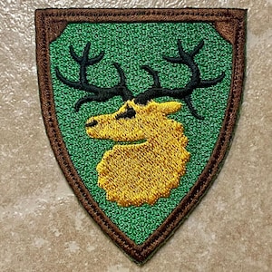 Può includere: Toppa ricamata con design a scudo, sfondo verde e bordo marrone. Presenta una testa di alce gialla con corna nere. Ideale per personalizzare giacche, borse o altri articoli in tessuto con un emblema unico.