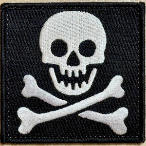 Può includere: Toppa quadrata nera con un teschio bianco e ossa incrociate. Il teschio ha grandi orbite e una mascella dettagliata. Le ossa incrociate sono posizionate sotto il teschio, un classico simbolo dei pirati.