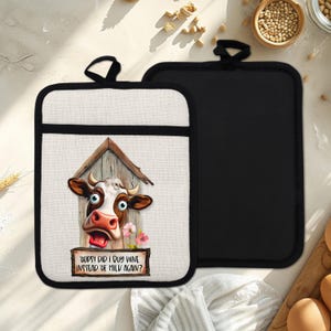 Puede incluir: Dos agarraderas rectangulares. Una presenta una vaca de dibujos animados con expresión de sorpresa, enmarcada por una estructura de madera y flores rosas. El texto dice "Oops! Did I buy wine instead of milk again?" La otra es negra.