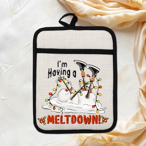 Puede incluir: Un agarrador de cocina cuadrado, de color crema, con borde negro y lazo para colgar negro. El diseño presenta un muñeco de nieve derritiéndose con esquís, luces navideñas y el texto "I'm Having a MELTDOWN!"
