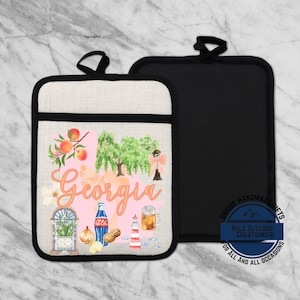 May include: Two pot holders. One is black, the other is off-white with a black border and a design featuring peaches, trees, and the word "Georgia" in cursive. The design also includes a lighthouse, a soda bottle, and a beer mug.