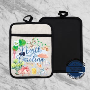 May include: Two pot holders. One is black, the other is beige with a black border and a North Carolina design. The design includes a pig with a bow, flowers, and the words "North Carolina" in blue script.
