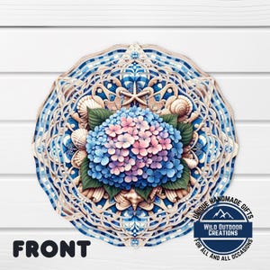 May include: A round, layered wooden wall art piece featuring a blue and pink hydrangea flower at the center. The design incorporates seashells and a blue and white checkered pattern. The text "FRONT" is visible at the bottom left.