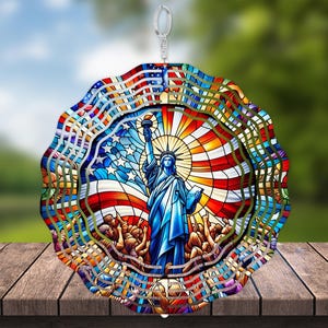 May include: A colorful metal wind spinner featuring a stained glass design of the Statue of Liberty and the American flag. The spinner has multiple layers and is designed to rotate in the wind.