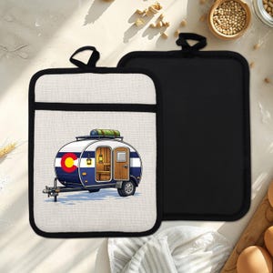 Op de afbeelding: Twee rechthoekige pannenlappen. Eén heeft een cartoon camper met de vlag van de staat Colorado, blauwe en witte strepen en een houten deur. De andere is effen zwart. Beide hebben een zwarte lus om op te hangen.