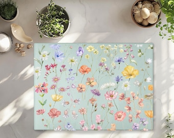 May include: A rectangular floral mat featuring a variety of colorful wildflowers in shades of pink, yellow, orange, and purple against a light blue background. The mat is surrounded by other decorative items.