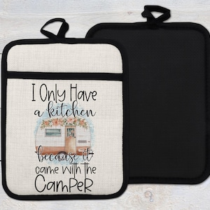 Può includere: Un sottopentola da cucina bianco con bordo nero e il testo "I only have a kitchen because it came with the Camper". Il sottopentola ha un motivo floreale e un'immagine di un camper in stile cartone animato.