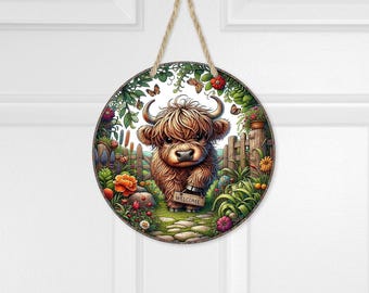 Colgante de puerta con diseño de vaca bebé de las Tierras Altas y letrero de bienvenida con motivos florales de jardín.