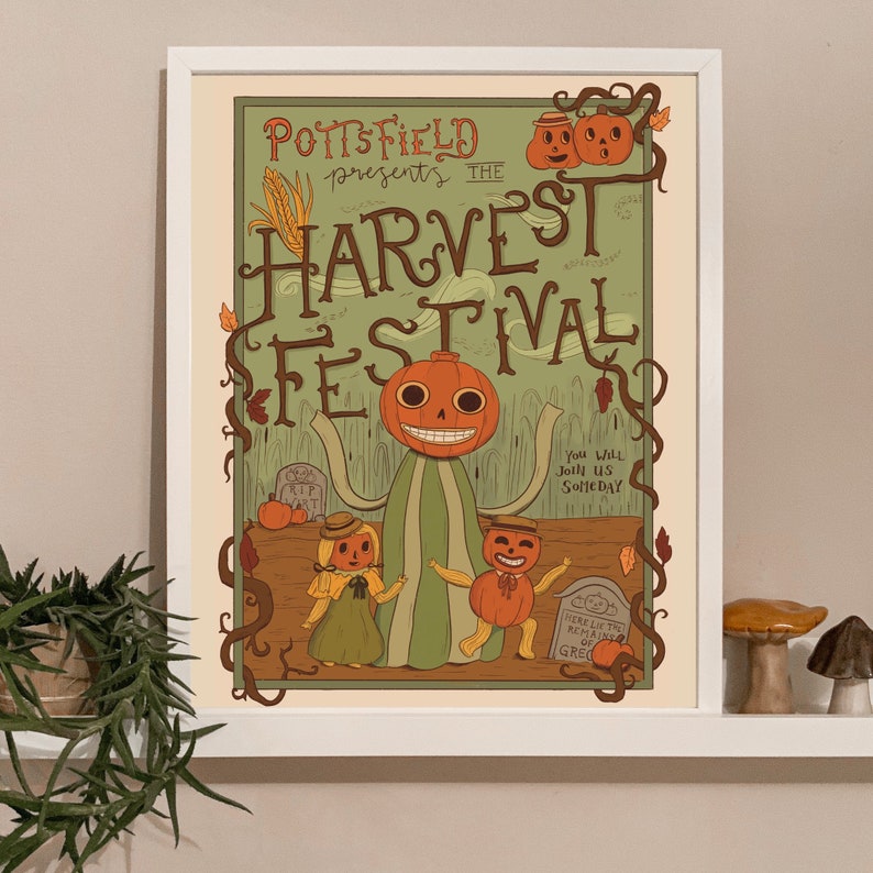 May include: A framed poster with a vintage-style illustration for the Pottsfield Harvest Festival. The artwork features a smiling pumpkin-headed figure, two smaller figures, and the text "Pottsfield presents the Harvest Festival."