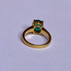 May include: A gold ring with a large, oval-shaped green gemstone set in a prong setting.