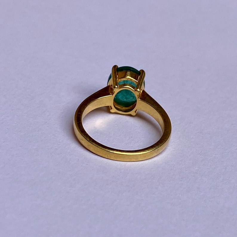 May include: A gold ring with a large, oval-shaped green gemstone set in a prong setting.
