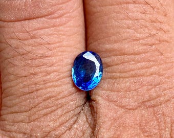 May include: A deep blue oval-shaped gemstone with a faceted cut.