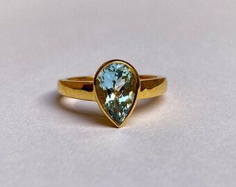 May include: A gold ring with a pear-shaped aquamarine gemstone.