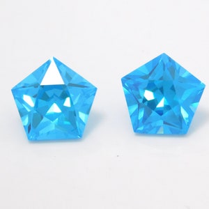 Pode incluir: Duas pedras preciosas azuis claras em forma de estrela com corte facetado.