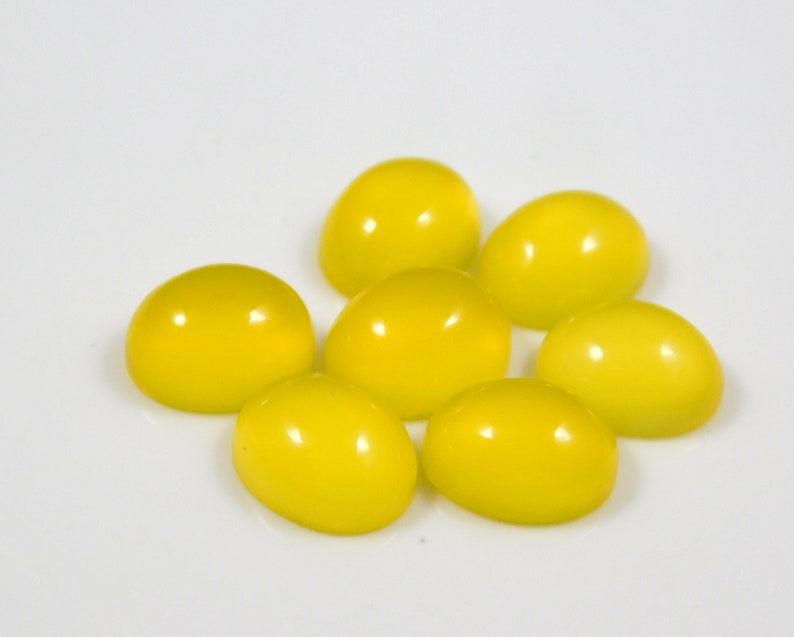 K&ouml;nnte beinhalten: Acht ovale, leuchtend gelbe Edelsteine auf einer wei&szlig;en Oberfl&auml;che.