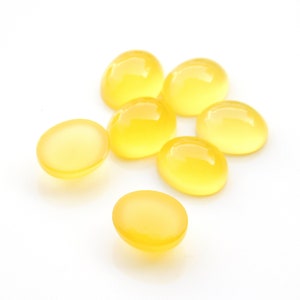 K&ouml;nnte beinhalten: Sieben gelbe ovale Cabochons, auch bekannt als polierte Steine, auf wei&szlig;em Hintergrund.