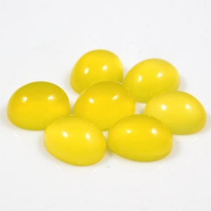 K&ouml;nnte beinhalten: Sieben leuchtend gelbe ovale Cabochon-Edelsteine auf wei&szlig;em Hintergrund.