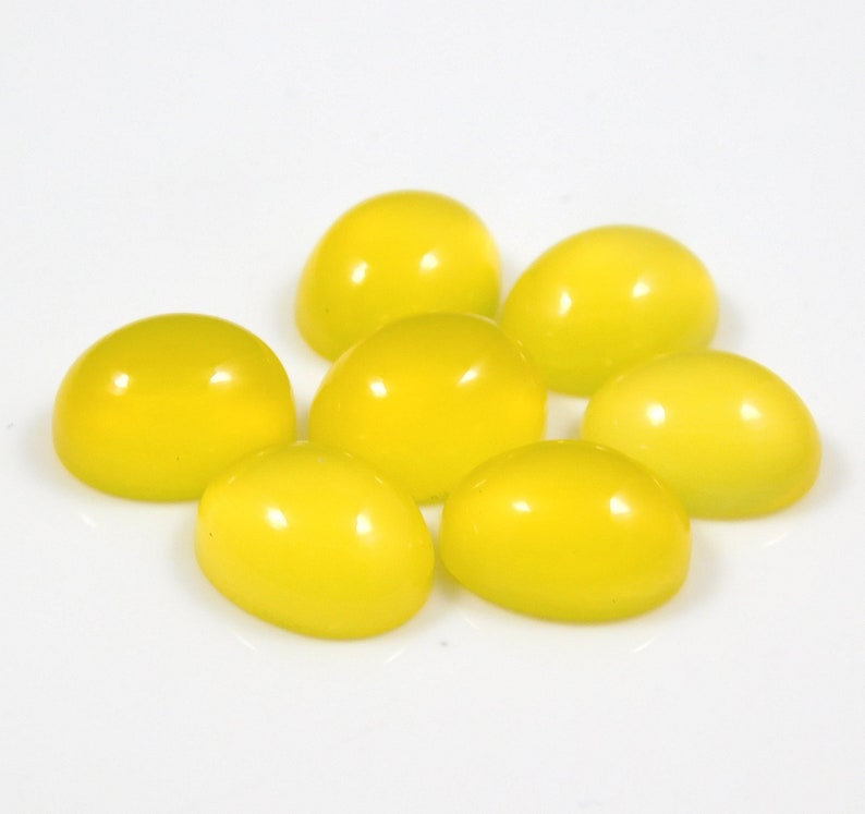 K&ouml;nnte beinhalten: Sieben leuchtend gelbe ovale Cabochon-Edelsteine auf wei&szlig;em Hintergrund.