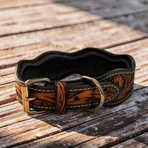 Peut inclure: Un collier de chien en cuir marron et noir avec un motif floral d&eacute;coratif. Le collier est dot&eacute; d'une boucle en laiton et d'un anneau en D pour l'attache de la laisse. Le collier mesure environ 2.5 cm de large.